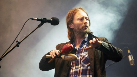 A man in a plaid shirt is holding a microphone.